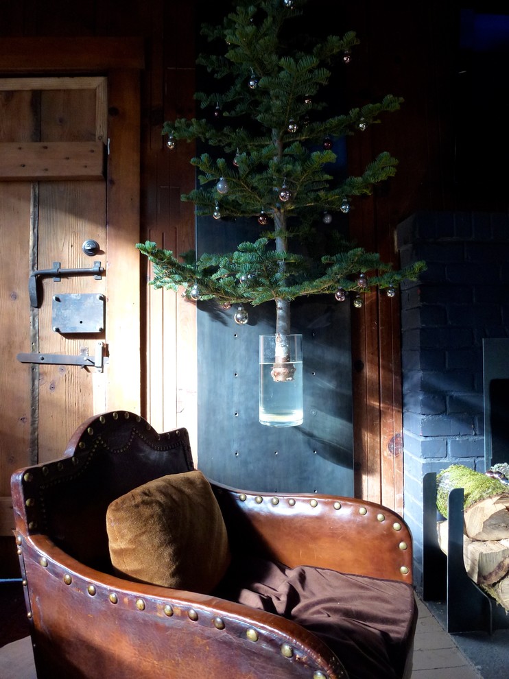 Immagine di un piccolo soggiorno rustico chiuso con sala formale, pareti nere, camino classico, cornice del camino in mattoni, nessuna TV e pavimento grigio