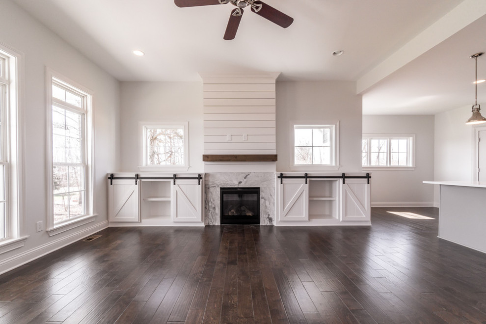 Offenes Klassisches Wohnzimmer mit weißer Wandfarbe, dunklem Holzboden, Kamin, Kaminumrandung aus Holzdielen, braunem Boden und Holzdielenwänden in Louisville