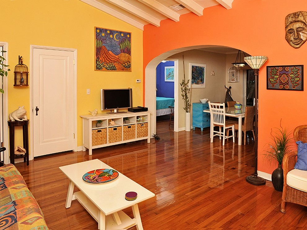 Example of an eclectic enclosed light wood floor living room design in Tampa with yellow walls and a media wall