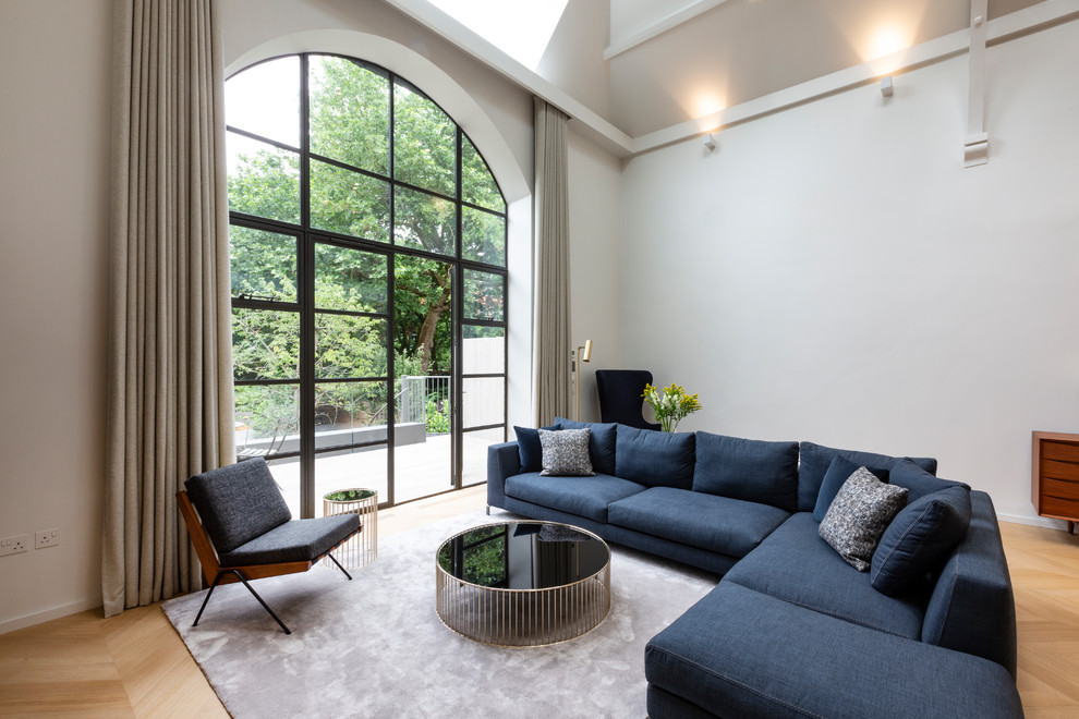 Идея дизайна: двухуровневая гостиная комната среднего размера в современном стиле с белыми стенами, светлым паркетным полом, бежевым полом и синим диваном