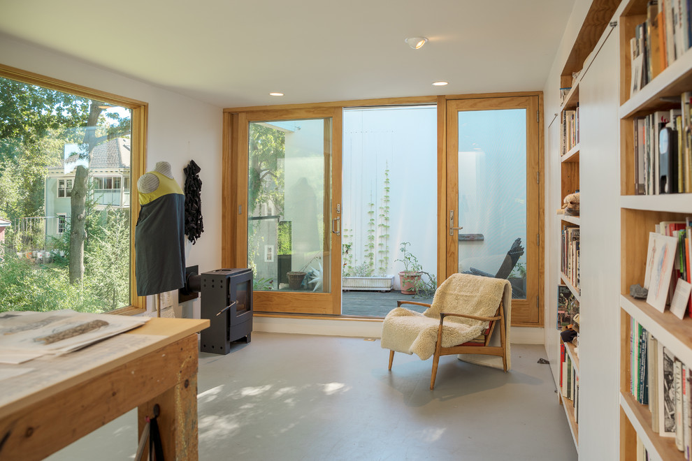 Idee per un soggiorno moderno di medie dimensioni e stile loft con libreria, pareti bianche, pavimento in compensato, stufa a legna e pavimento grigio