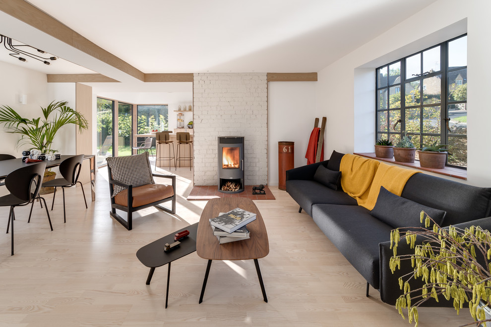 Inspiration for a mid-sized contemporary open concept light wood floor and beige floor living room remodel in Other with white walls, a wood stove and a brick fireplace