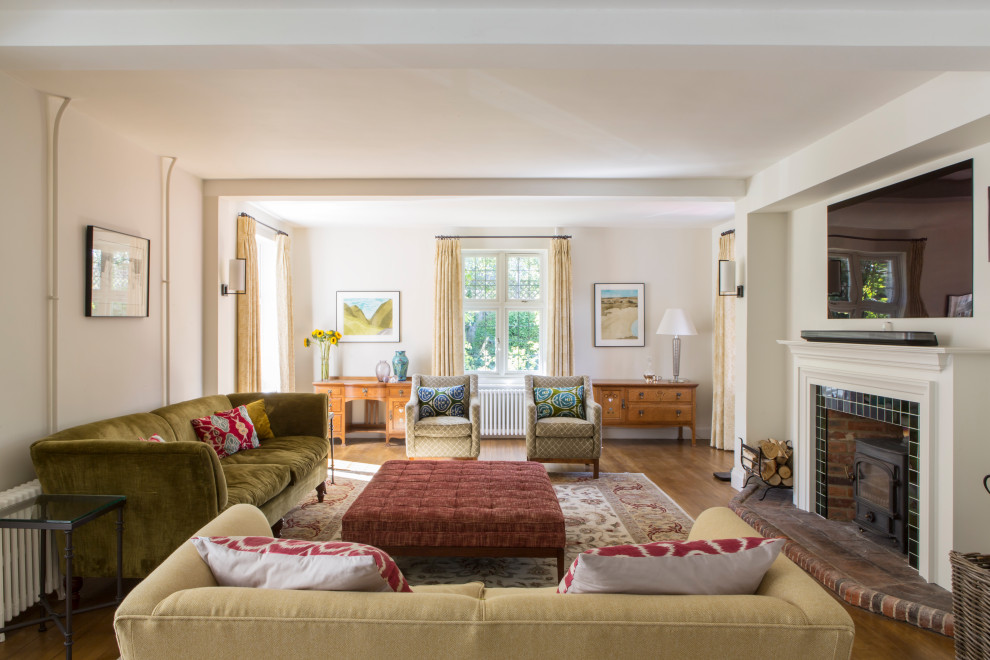 Klassisches Wohnzimmer mit weißer Wandfarbe, braunem Holzboden, Kaminofen, gefliester Kaminumrandung, TV-Wand und braunem Boden in Oxfordshire