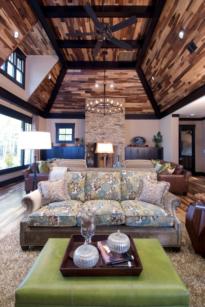 Ejemplo de salón para visitas abierto de estilo americano con paredes beige, suelo de madera clara, todas las chimeneas, marco de chimenea de piedra y televisor retractable