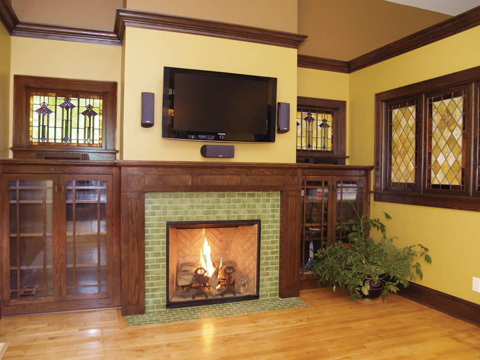 Источник вдохновения для домашнего уюта: двухуровневая гостиная комната среднего размера в классическом стиле с желтыми стенами, светлым паркетным полом, стандартным камином, фасадом камина из плитки, телевизором на стене и коричневым полом