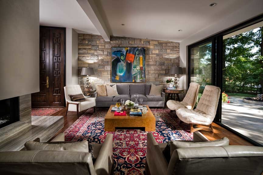 На фото: большая открытая гостиная комната в стиле ретро с двусторонним камином и фасадом камина из камня