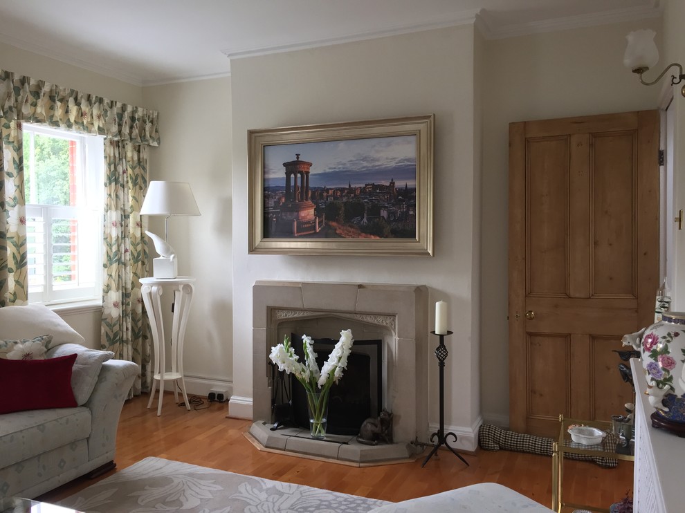 Klassisches Wohnzimmer mit beiger Wandfarbe, braunem Holzboden, Kamin, Kaminumrandung aus Stein und TV-Wand in Buckinghamshire