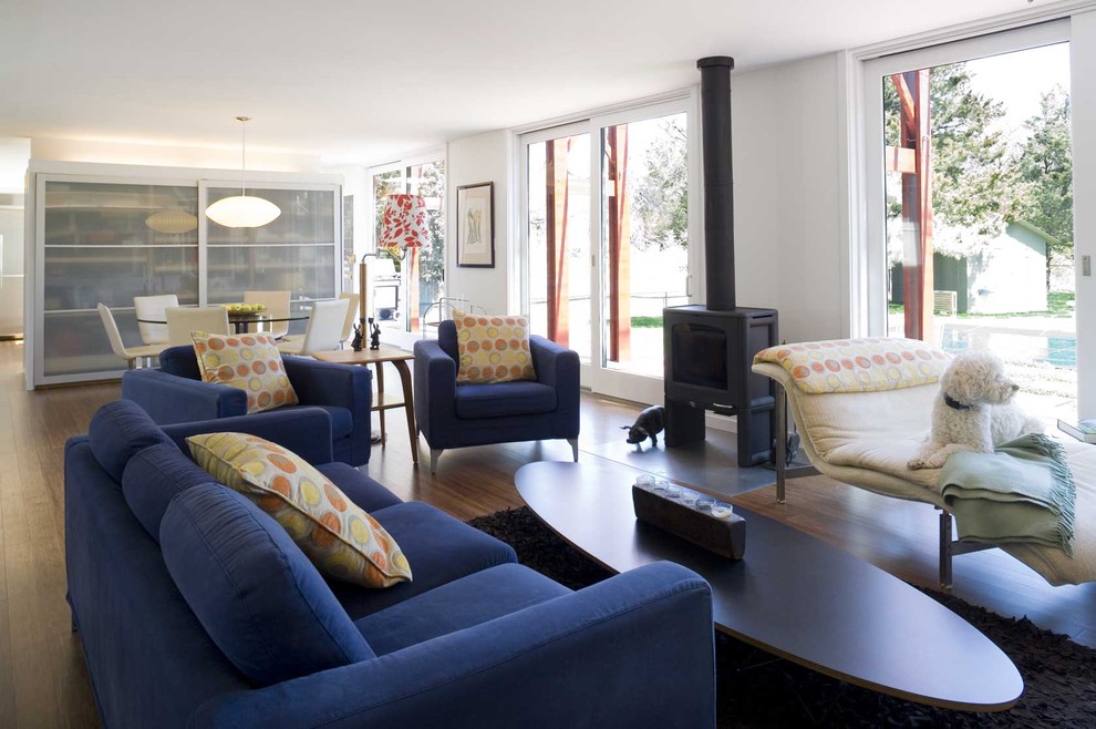 Источник вдохновения для домашнего уюта: гостиная комната в стиле модернизм с полом из бамбука, печью-буржуйкой и синим диваном