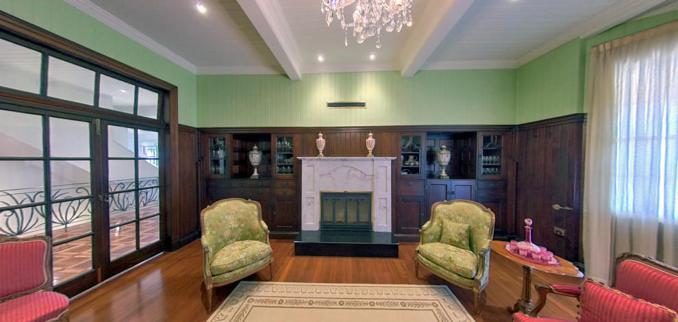 Großes, Repräsentatives, Abgetrenntes Klassisches Wohnzimmer mit grüner Wandfarbe, braunem Holzboden, Kamin, Kaminumrandung aus Stein, Holzdielendecke und vertäfelten Wänden in Brisbane