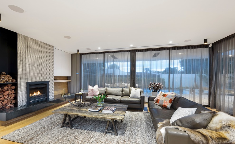 Aménagement d'un grand salon contemporain ouvert avec un mur blanc, un sol en bois brun, une cheminée standard, un manteau de cheminée en carrelage et un sol marron.