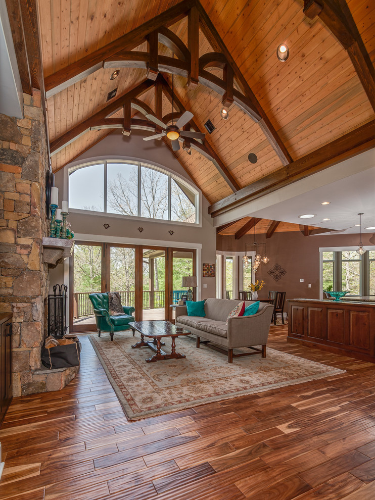 Example of a mid-sized arts and crafts open concept medium tone wood floor living room design in Other with beige walls, a standard fireplace and a stone fireplace