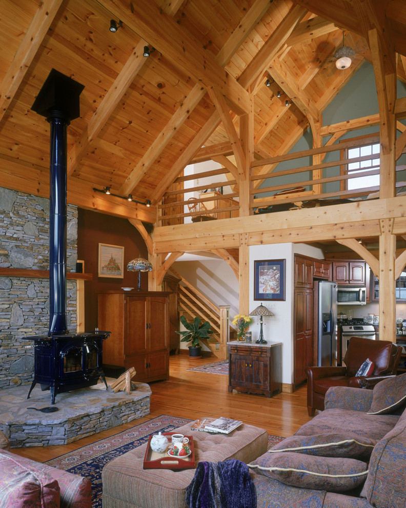 Imagen de salón tipo loft de estilo americano grande con paredes marrones, suelo de madera en tonos medios, estufa de leña y marco de chimenea de piedra