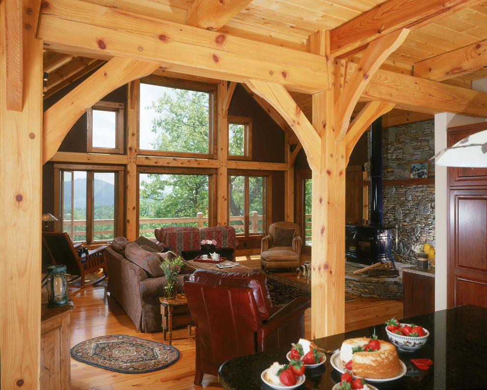 Immagine di un grande soggiorno stile americano stile loft con pareti marroni, pavimento in legno massello medio, stufa a legna e cornice del camino in pietra