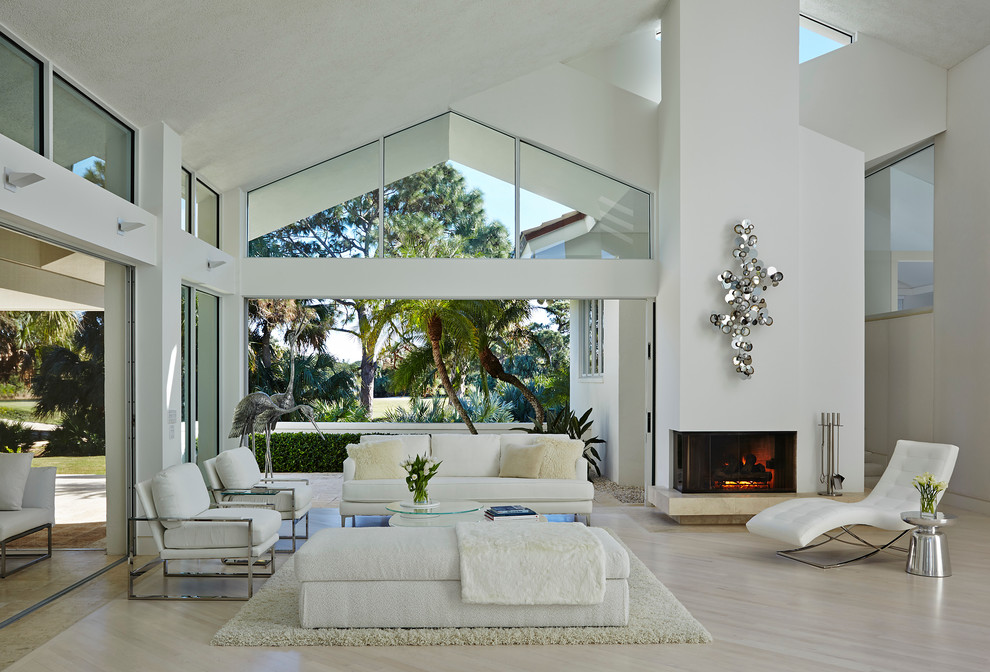 Repräsentatives, Offenes, Großes, Fernseherloses Modernes Wohnzimmer mit weißer Wandfarbe, hellem Holzboden, Kamin, verputzter Kaminumrandung und beigem Boden in Miami