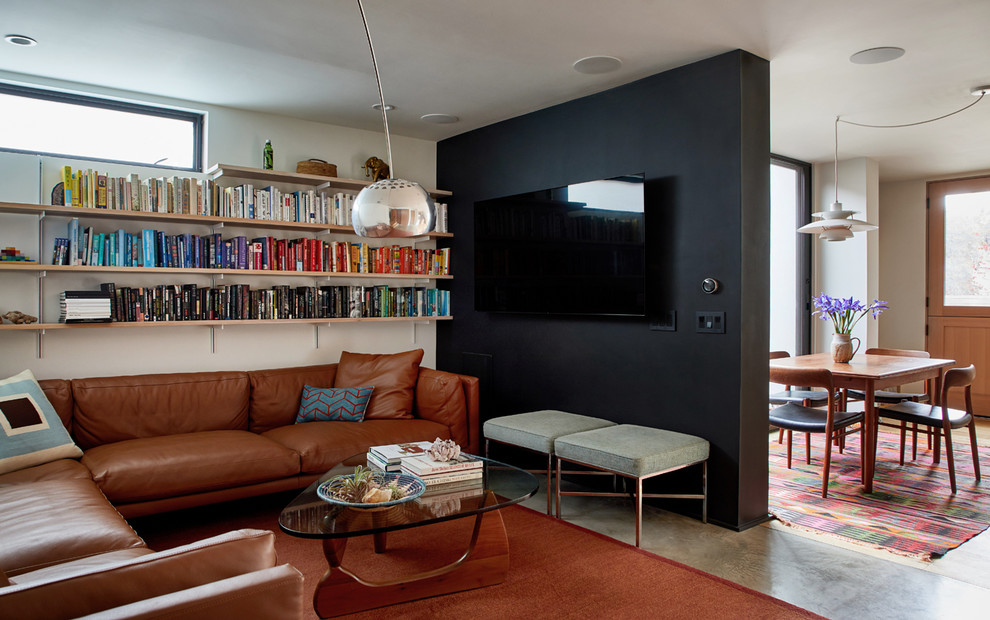 Große, Offene Moderne Bibliothek ohne Kamin mit schwarzer Wandfarbe, Betonboden, TV-Wand und grauem Boden in Los Angeles