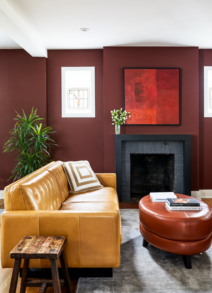 Modern inredning av ett mellanstort allrum med öppen planlösning, med röda väggar, mellanmörkt trägolv, en standard öppen spis, en spiselkrans i sten och brunt golv
