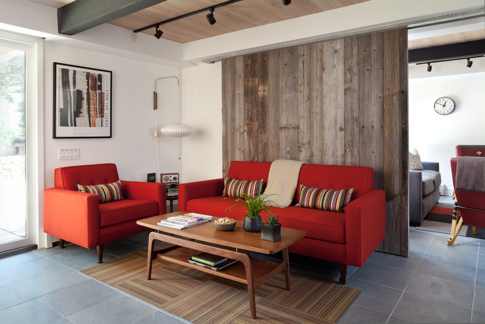 デンバーにある中くらいなミッドセンチュリースタイルのおしゃれな独立型リビング (白い壁、テレビなし、スレートの床、コーナー設置型暖炉、タイルの暖炉まわり、赤いソファ) の写真