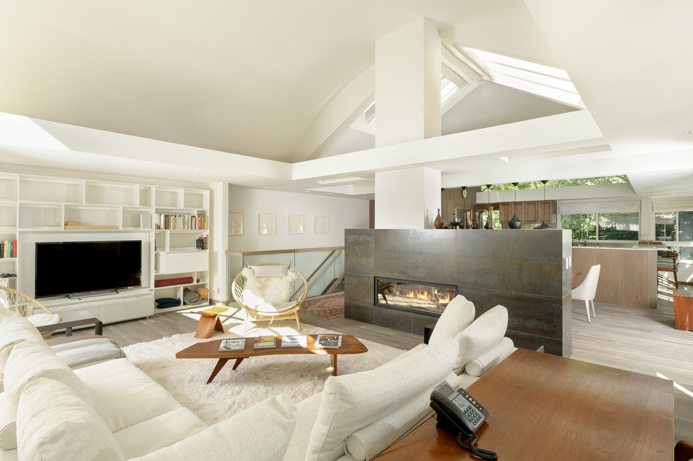 Cette photo montre un salon tendance de taille moyenne et ouvert avec un mur blanc, un sol en bois brun, une cheminée double-face, un manteau de cheminée en carrelage et un téléviseur encastré.
