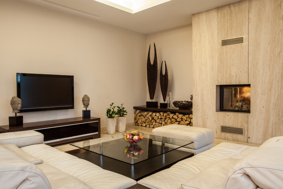Modelo de salón contemporáneo con paredes beige, chimenea de doble cara, marco de chimenea de piedra, televisor colgado en la pared y suelo beige