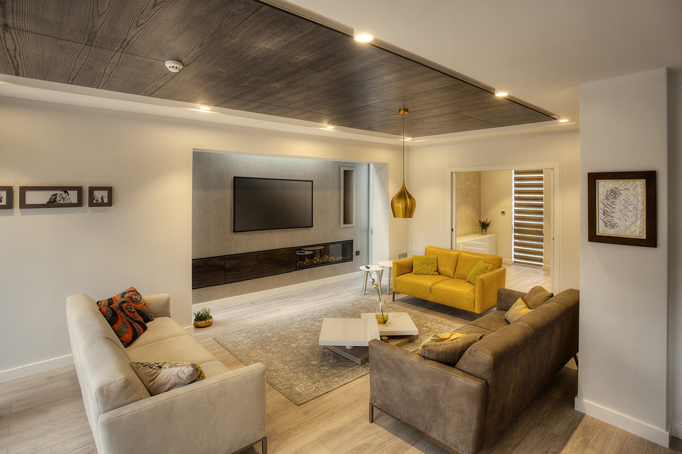 Foto de salón para visitas cerrado contemporáneo de tamaño medio con paredes grises, suelo de madera clara y televisor colgado en la pared