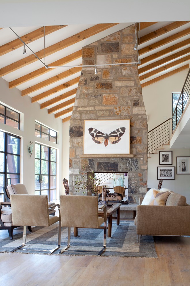 Inspiration for a rustic formal open plan living room in Denver with beige walls, medium hardwood flooring, a two-sided fireplace and a stone fireplace surround.