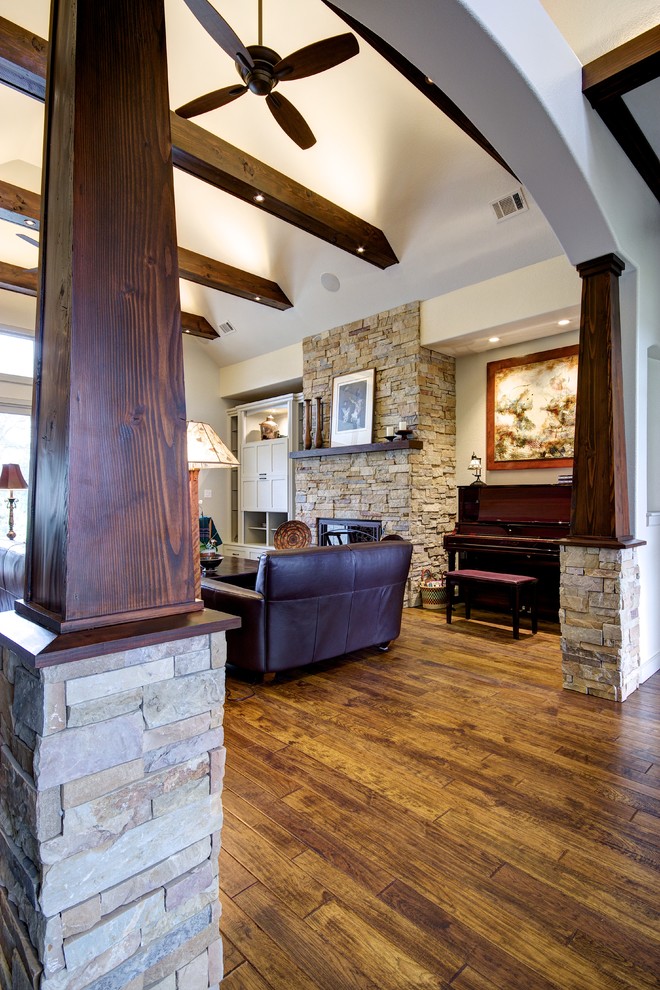 Inspiration for a large craftsman open concept medium tone wood floor living room remodel in Austin with beige walls, a standard fireplace, a stone fireplace and a concealed tv