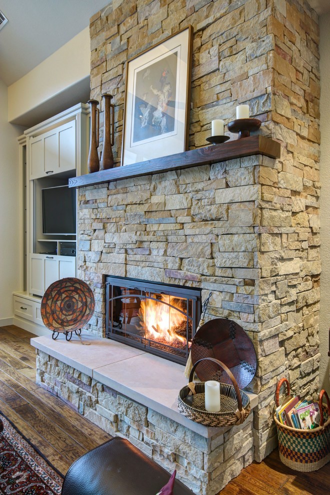 Example of a large arts and crafts open concept medium tone wood floor living room design in Austin with beige walls, a standard fireplace, a stone fireplace and a concealed tv
