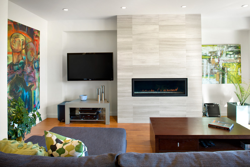 Imagen de salón abierto moderno con chimenea lineal, televisor colgado en la pared, paredes blancas, suelo de madera en tonos medios y marco de chimenea de piedra