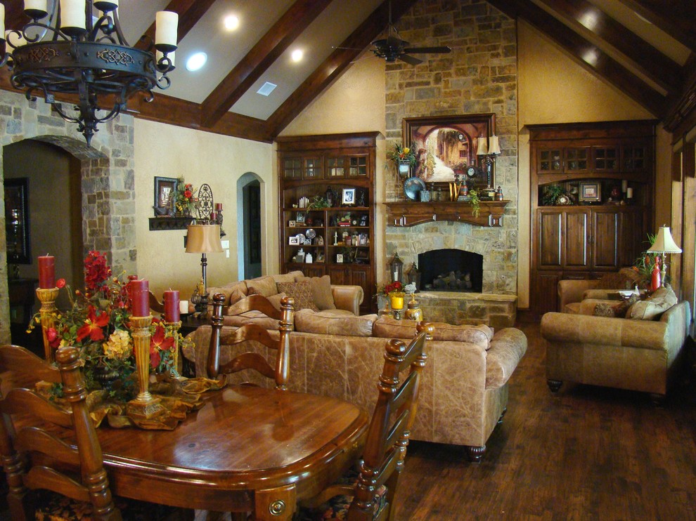 Imagen de salón para visitas abierto tradicional grande con paredes amarillas, suelo de madera en tonos medios, todas las chimeneas y marco de chimenea de piedra
