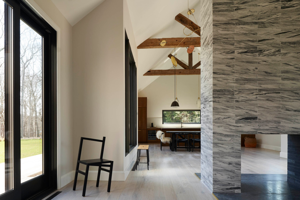 Imagen de salón para visitas abierto y abovedado moderno grande con paredes blancas, suelo de madera clara, chimenea de doble cara, marco de chimenea de piedra y suelo blanco
