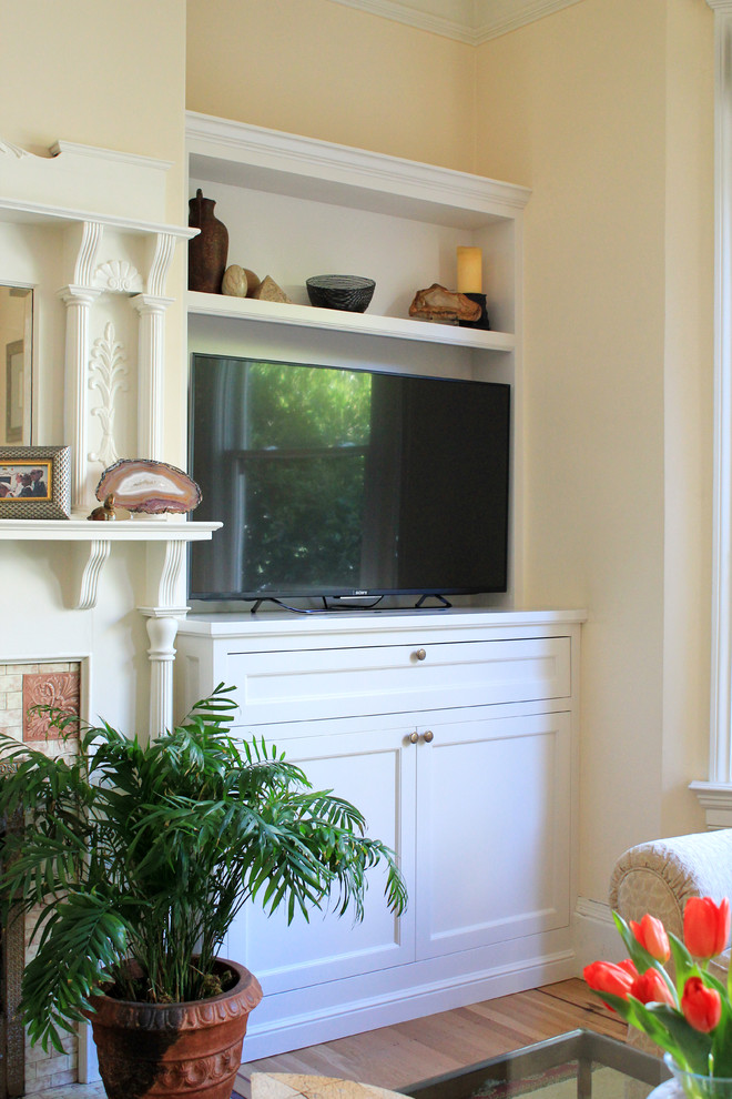 Immagine di un piccolo soggiorno tradizionale chiuso con pareti beige, pavimento in legno massello medio, stufa a legna, cornice del camino piastrellata e TV autoportante