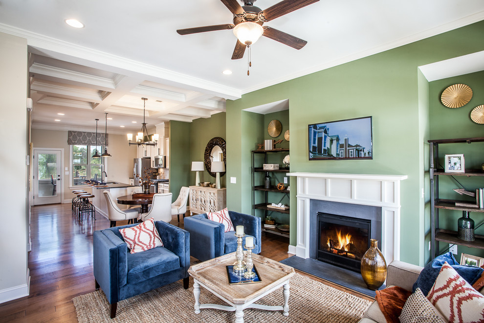 Kleines, Offenes Klassisches Wohnzimmer mit grüner Wandfarbe, braunem Holzboden, Kamin, Kaminumrandung aus Holz und TV-Wand in Atlanta