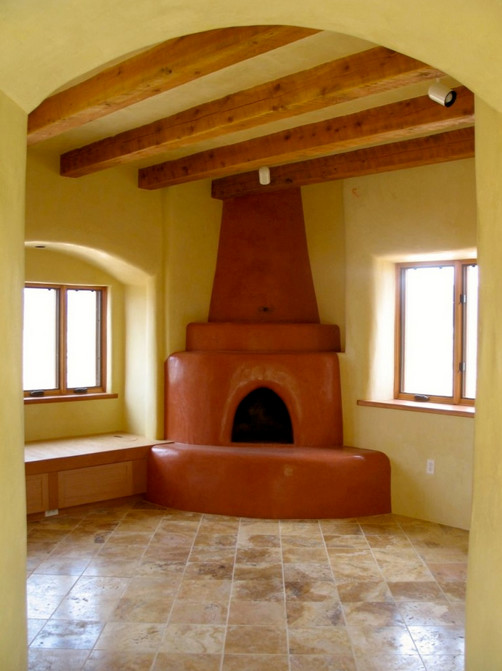 アルバカーキにあるお手頃価格の中くらいなおしゃれな独立型リビング (黄色い壁、トラバーチンの床、薪ストーブ、コンクリートの暖炉まわり) の写真