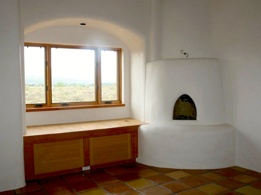 Foto på ett mellanstort separat vardagsrum, med vita väggar, klinkergolv i terrakotta, en öppen vedspis och en spiselkrans i betong