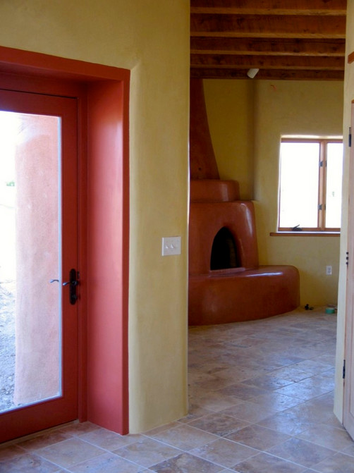 Modelo de salón cerrado de tamaño medio con paredes amarillas, suelo de travertino, estufa de leña y marco de chimenea de hormigón