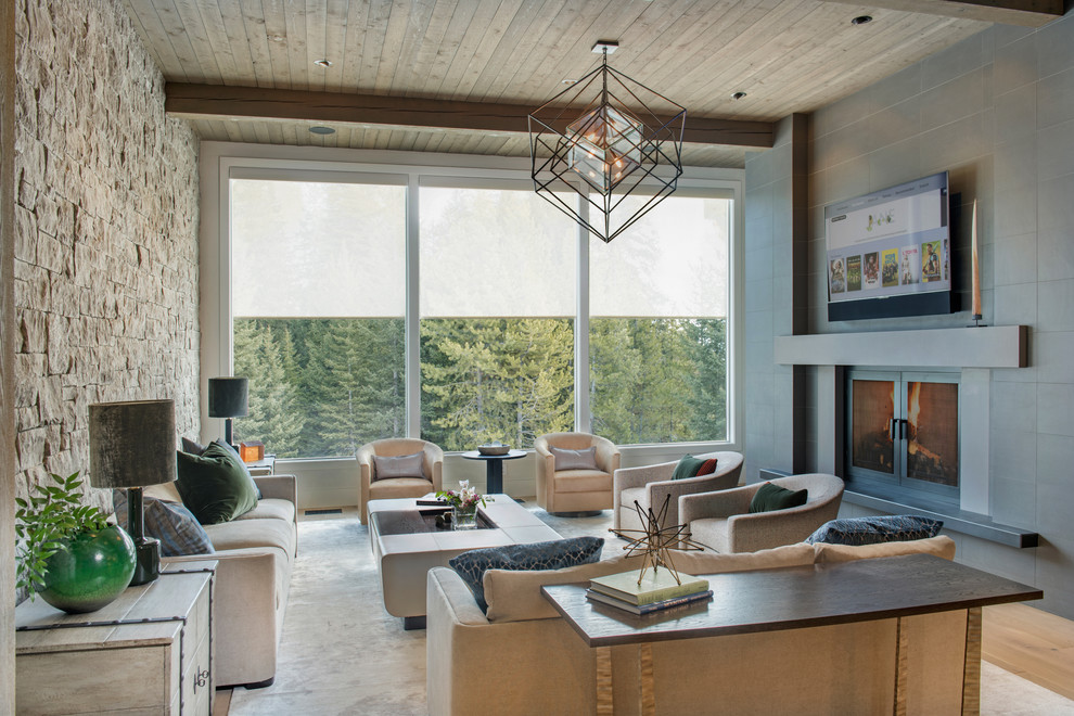 Cette image montre un grand salon design ouvert avec un mur gris, un sol en bois brun, une cheminée double-face, un manteau de cheminée en carrelage, un téléviseur fixé au mur et un sol marron.