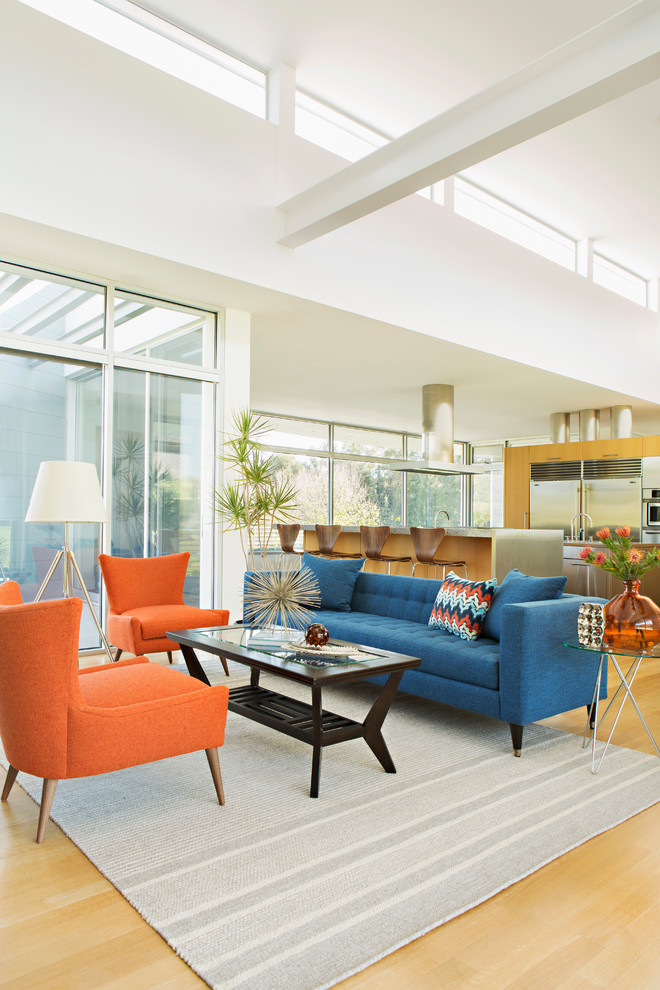 Идея дизайна: парадная, открытая гостиная комната в стиле ретро с белыми стенами, светлым паркетным полом и синим диваном