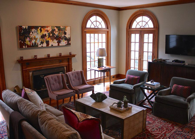 Exemple d'un grand salon éclectique avec une salle de réception, un mur beige, un sol en bois brun, une cheminée standard, un manteau de cheminée en bois et un téléviseur fixé au mur.