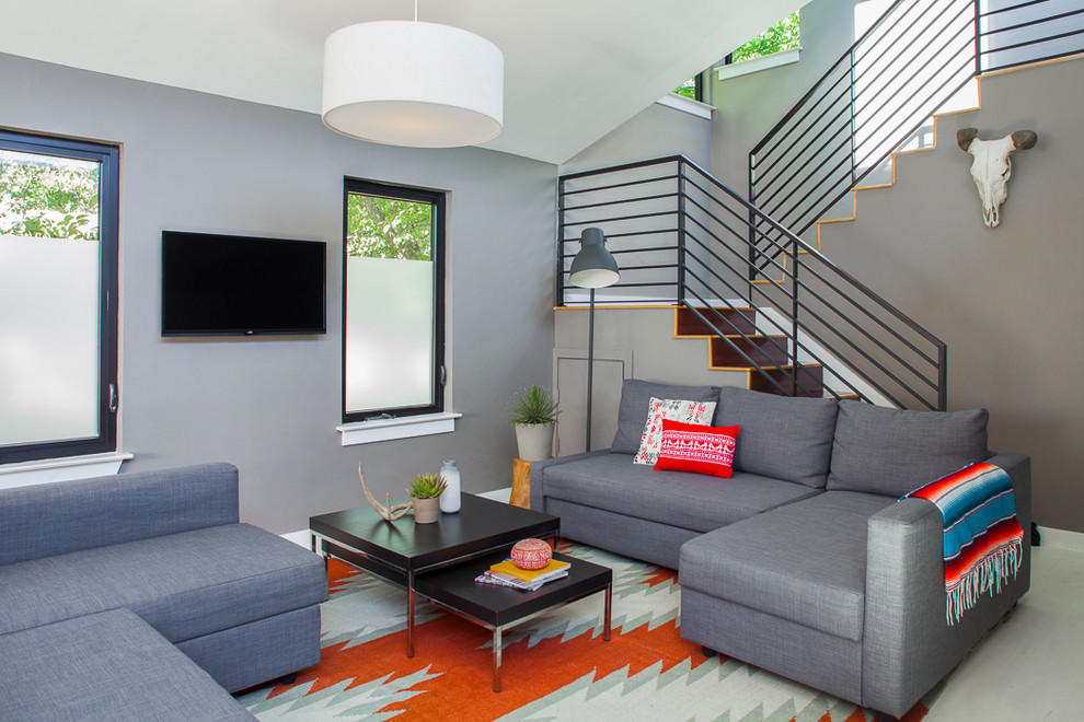 Foto di un piccolo soggiorno moderno con pareti grigie, pavimento in legno verniciato, nessun camino e TV a parete
