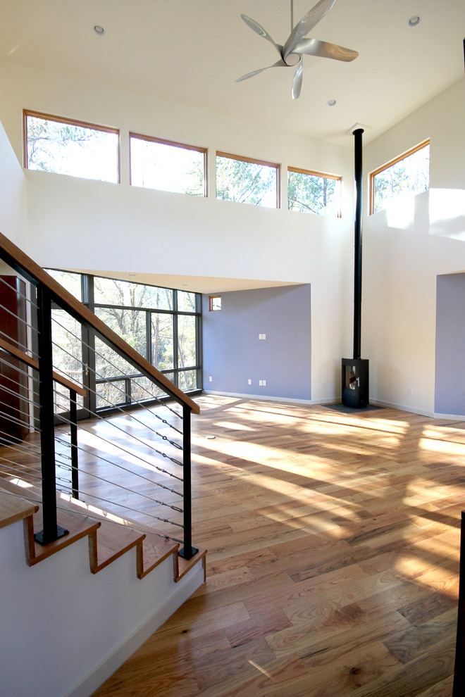 Mittelgroßes, Offenes Modernes Wohnzimmer mit lila Wandfarbe, braunem Holzboden und Kaminofen in Atlanta