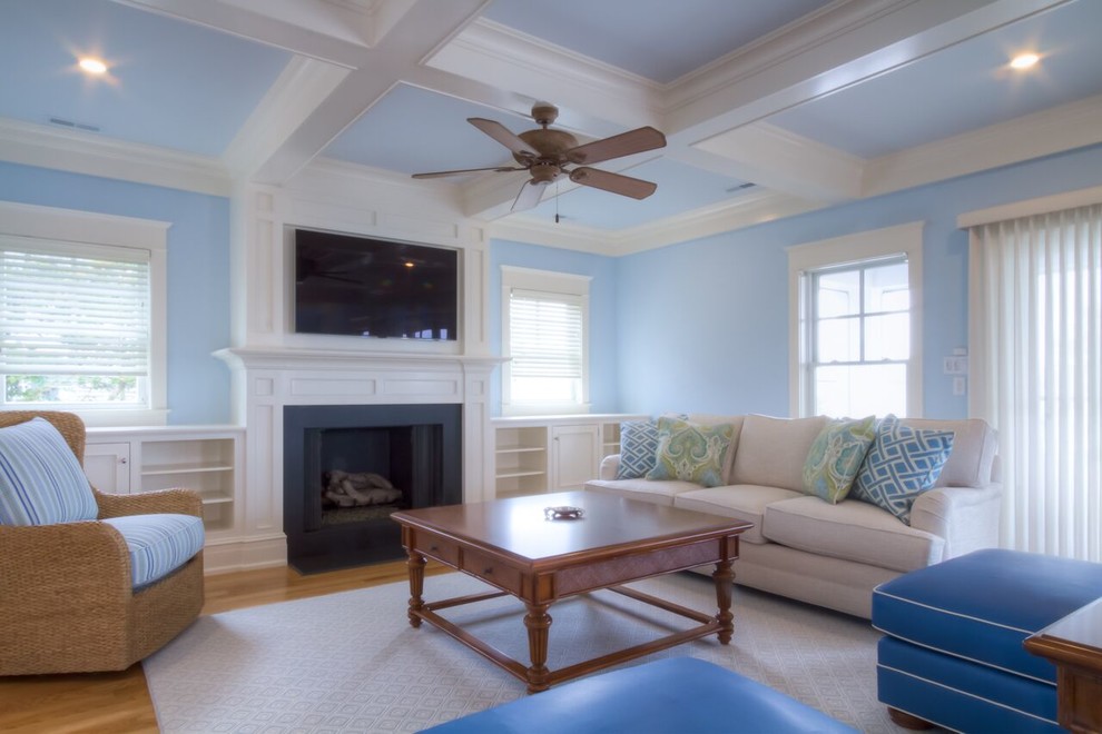 Idee per un soggiorno stile marinaro con pareti blu, parquet chiaro, camino classico e parete attrezzata