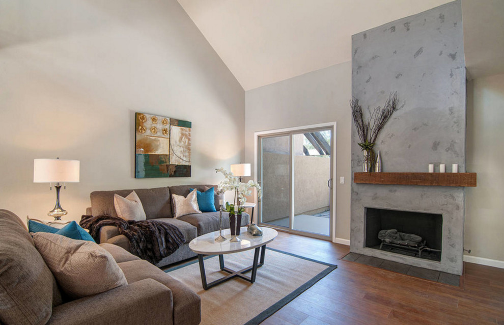 Mittelgroßes, Repräsentatives, Offenes Modernes Wohnzimmer mit grauer Wandfarbe, braunem Holzboden, Kamin und verputzter Kaminumrandung in San Diego