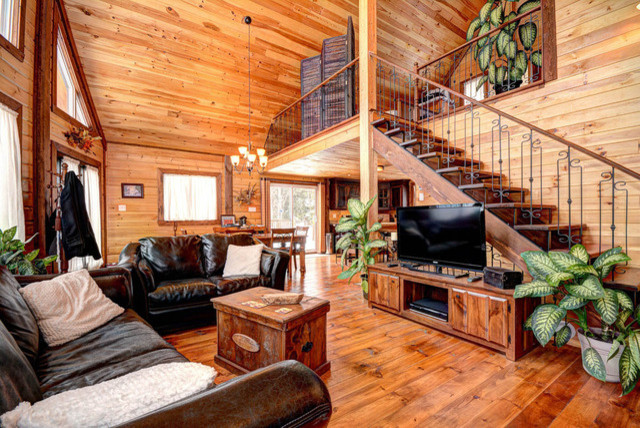 Idee per un piccolo soggiorno rustico aperto con pareti marroni e pavimento in legno verniciato