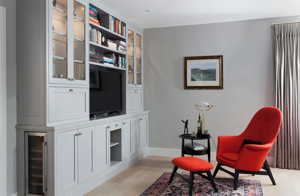 Imagen de salón clásico renovado con paredes grises, suelo de madera clara y televisor independiente