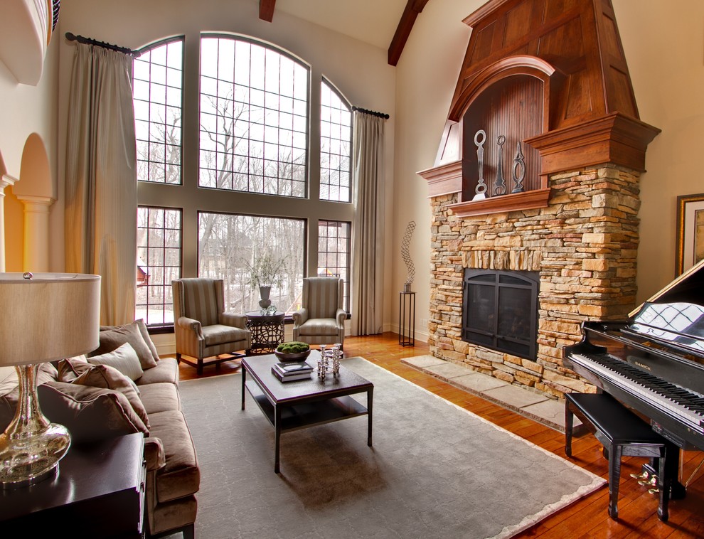 Imagen de salón con rincón musical clásico sin televisor con suelo de madera en tonos medios, todas las chimeneas, marco de chimenea de piedra y arcos