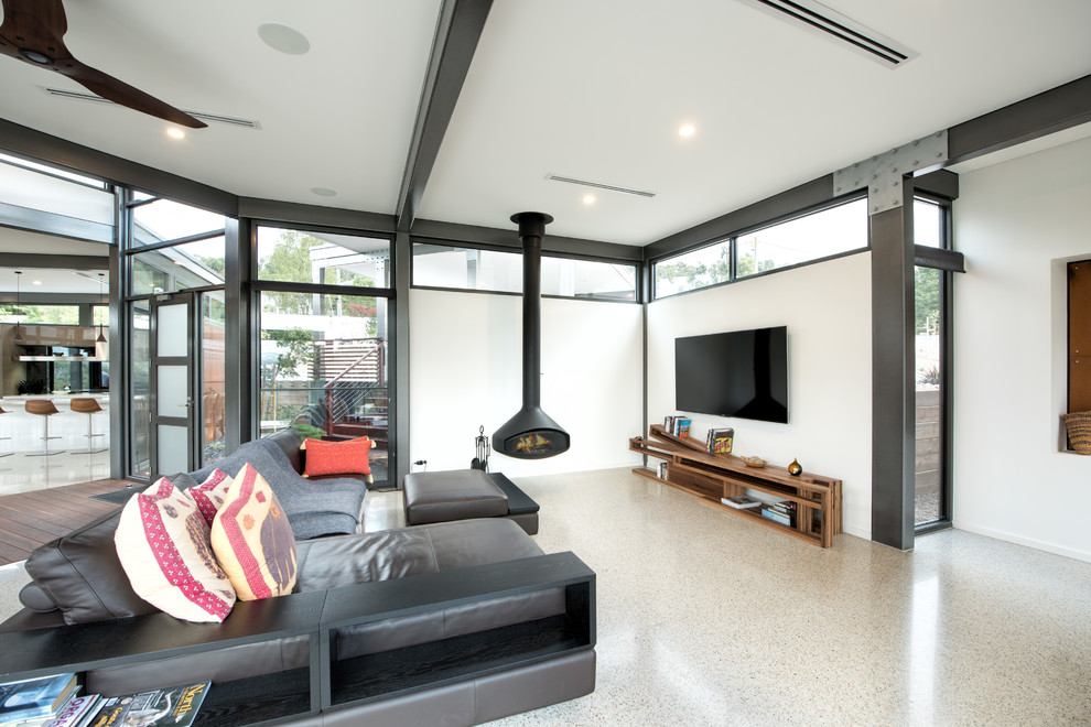 Esempio di un ampio soggiorno minimal aperto con pareti bianche, pavimento in cemento, camino sospeso, cornice del camino in metallo e TV a parete