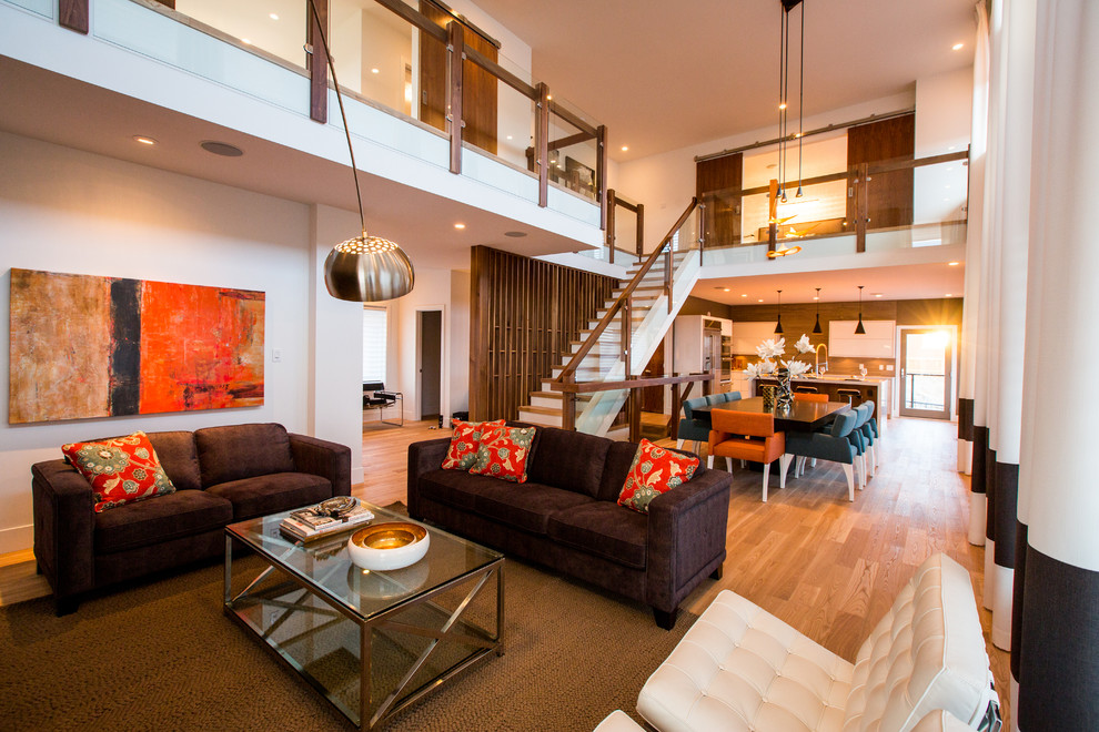 Стильный дизайн: гостиная комната в современном стиле с белыми стенами, паркетным полом среднего тона и коричневым диваном - последний тренд