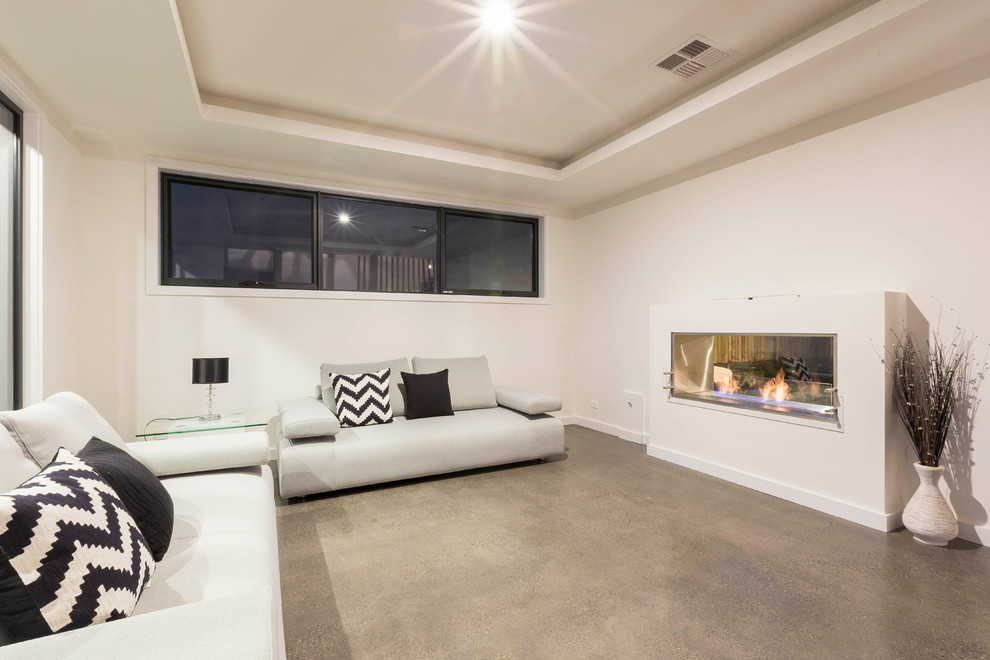 Cette image montre un salon design ouvert avec une salle de réception, un mur blanc, sol en béton ciré, une cheminée double-face, un manteau de cheminée en plâtre et aucun téléviseur.