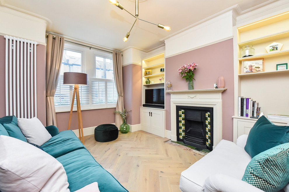 Mittelgroßes, Repräsentatives Klassisches Wohnzimmer mit rosa Wandfarbe, hellem Holzboden, Kamin, verputzter Kaminumrandung, freistehendem TV und beigem Boden in London