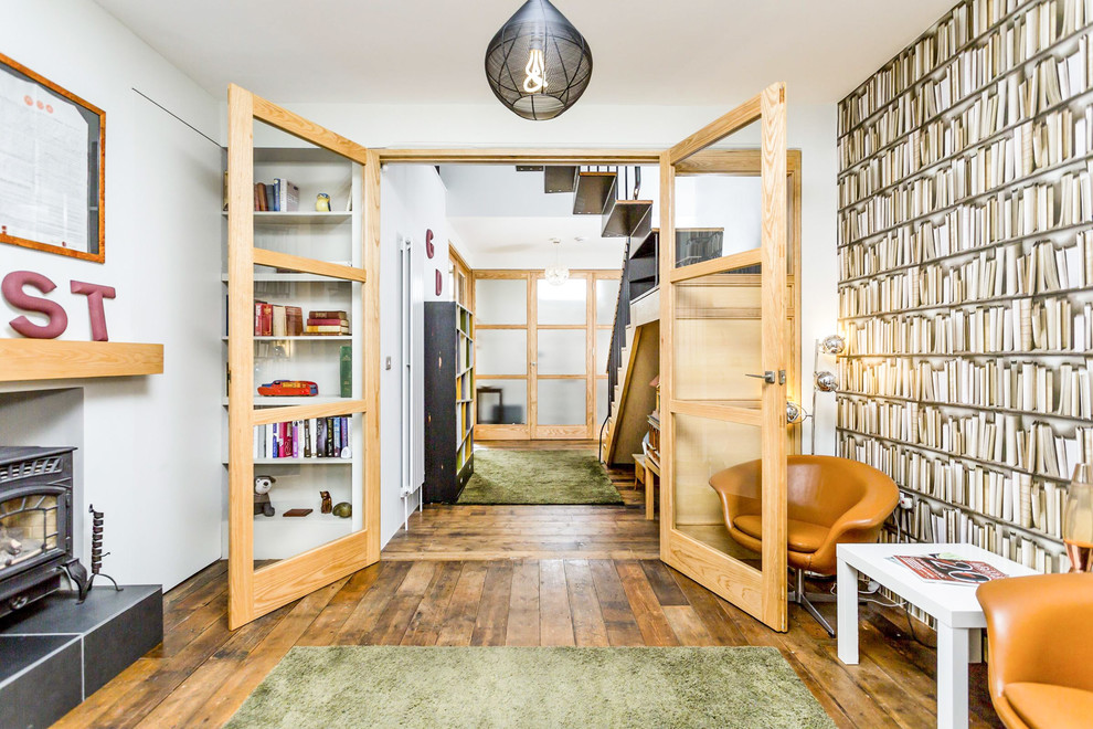 Cette image montre un salon design fermé avec un sol en bois brun et un poêle à bois.